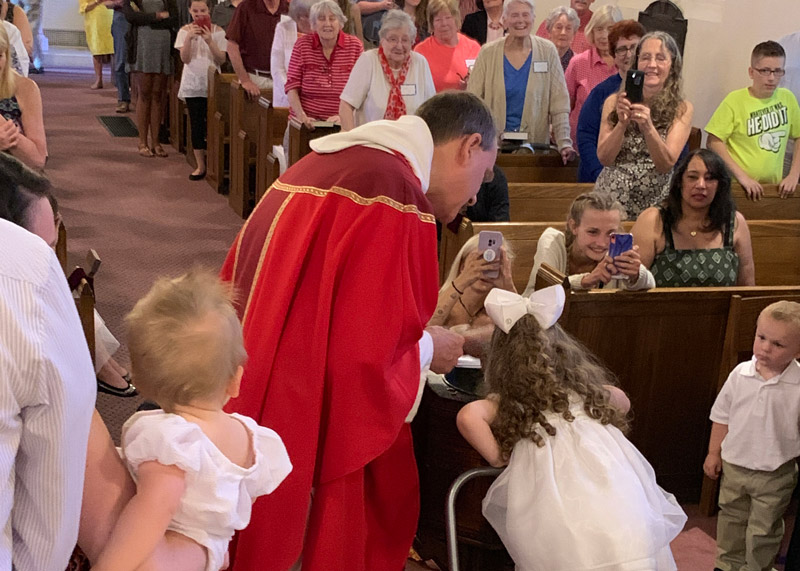 young girl receiving baptism with family gathered around and taking photos