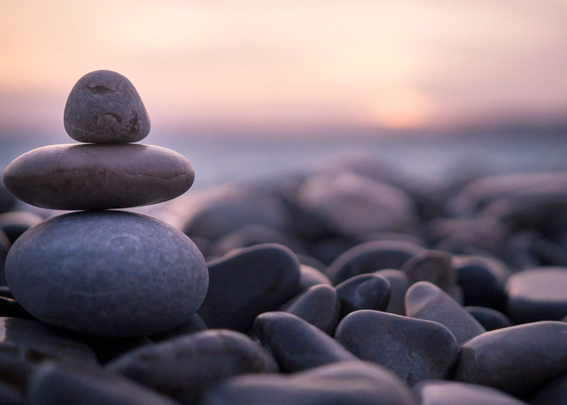 meditative scene of stacked smooth stones by the ocean at sunset